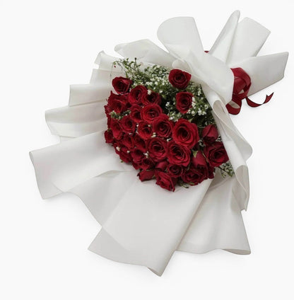 Bouquet of red roses shaped like a heart with white ribbons on a white background