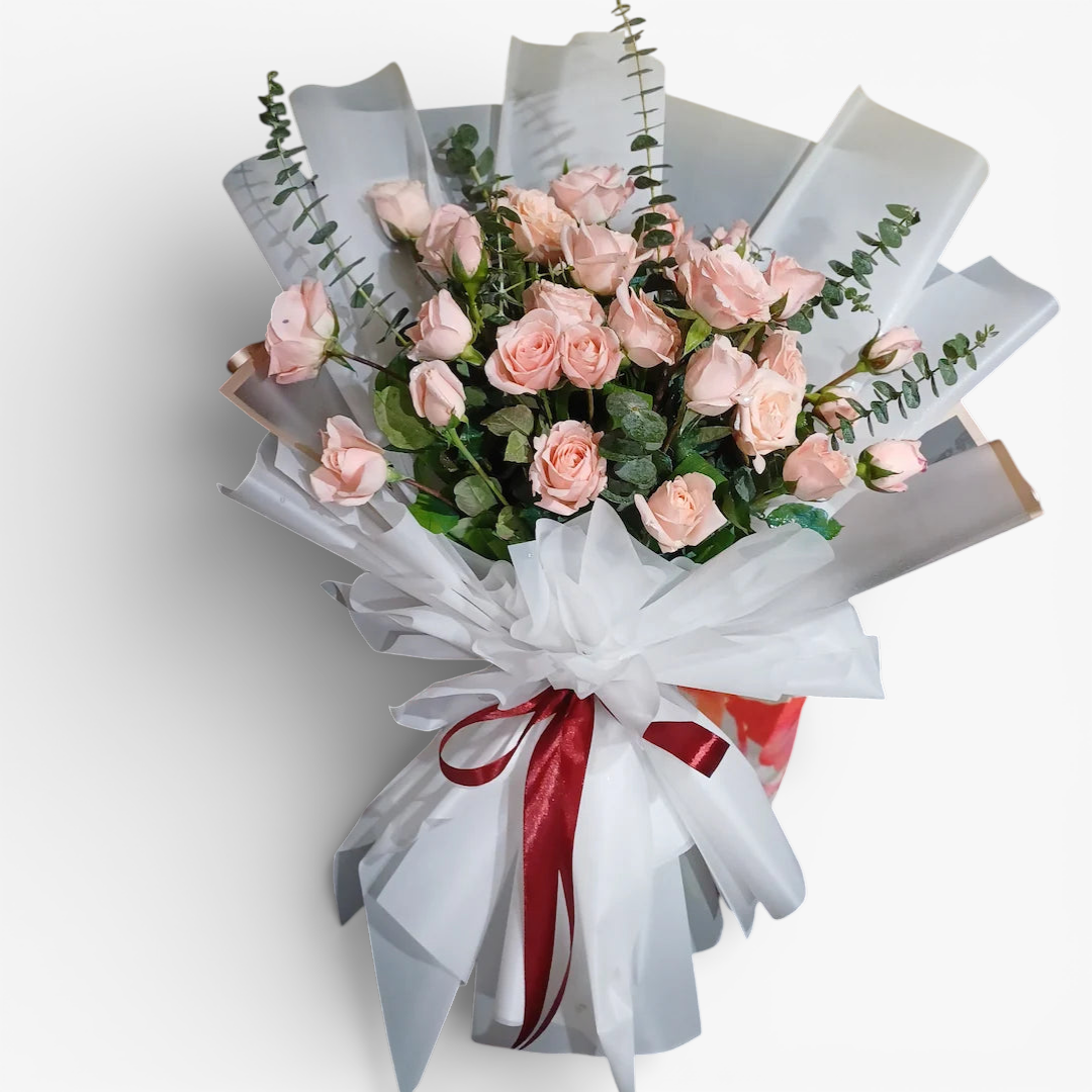 The Flowercart Lovely Spark bouquet with 24 baby pink roses and eucalyptus, wrapped in white paper with a burgundy ribbon.
