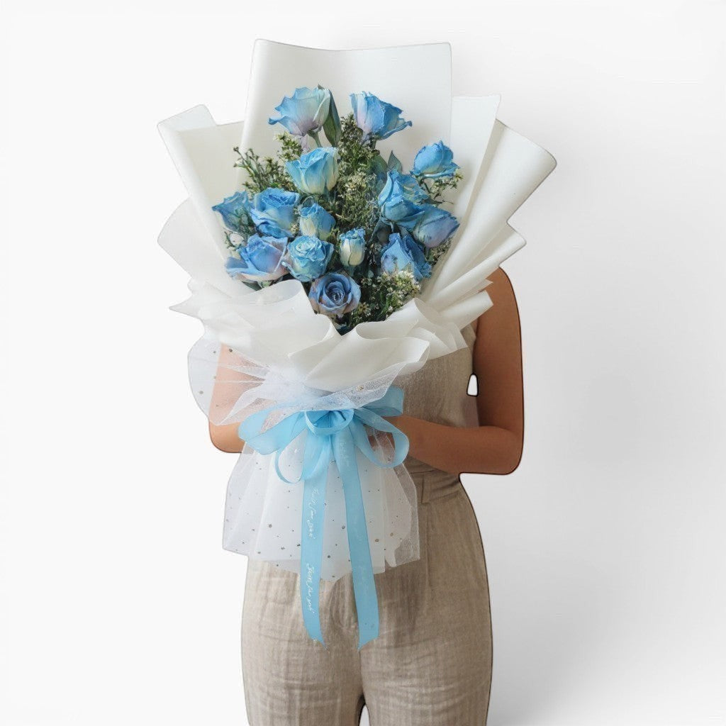 The Flowercart 12 blue roses bouquet with white wrapping and blue ribbon, perfect for unique occasions.