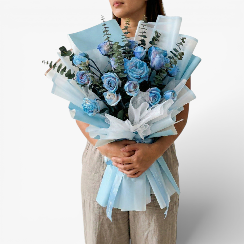 The Flowercart's unique bouquet of 24 blue spray roses and eucalyptus, wrapped in light blue and white paper.