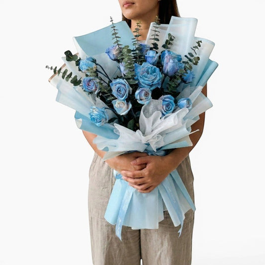 The Flowercart's unique bouquet of 24 blue spray roses and eucalyptus, wrapped in light blue and white paper.