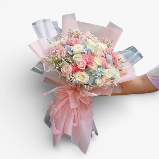 The Flowercart Pastel Dreams bouquet with pink roses, white roses, pink carnations, blue hydrangea, and baby's breath.