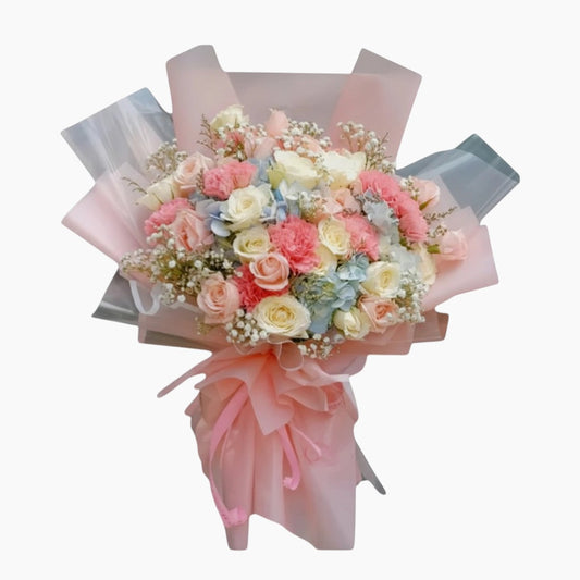 The Flowercart Pastel Dreams bouquet with pink roses, white roses, pink carnations, blue hydrangea, and baby's breath.