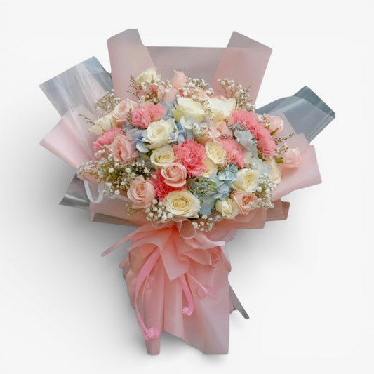 The Flowercart Pastel Dreams bouquet with pink roses, white roses, pink carnations, blue hydrangea, and baby's breath.