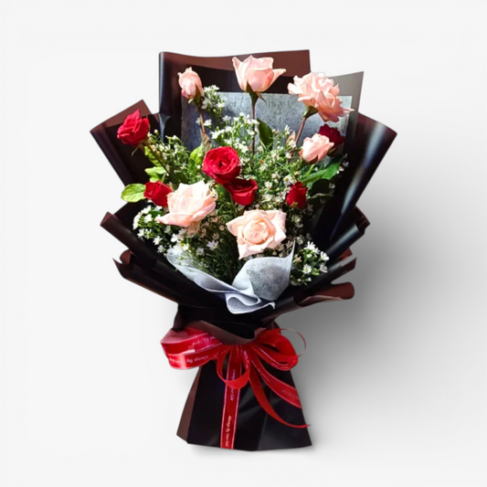 The Flowercart Harmony bouquet: 12 pink and red roses with greenery, white fillers, wrapped in black paper and tied with a red ribbon.