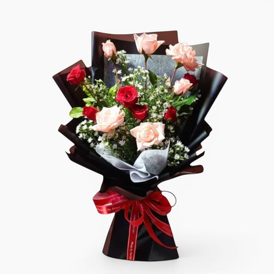 The Flowercart Harmony bouquet: 12 pink and red roses with greenery, white fillers, wrapped in black paper and tied with a red ribbon.