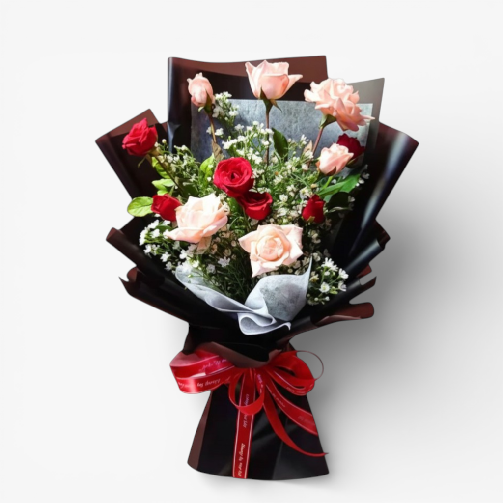 The Flowercart Harmony bouquet: 12 pink and red roses with greenery, white fillers, wrapped in black paper and tied with a red ribbon.