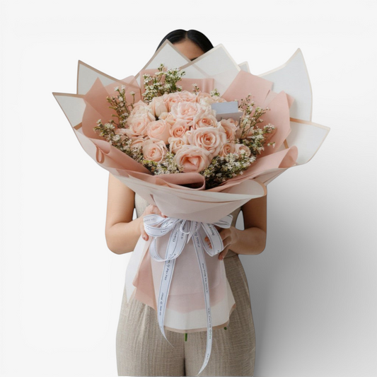 The Flowercart 50 pink roses bouquet with baby's breath, elegantly wrapped in pink and white paper, tied with a white ribbon.
