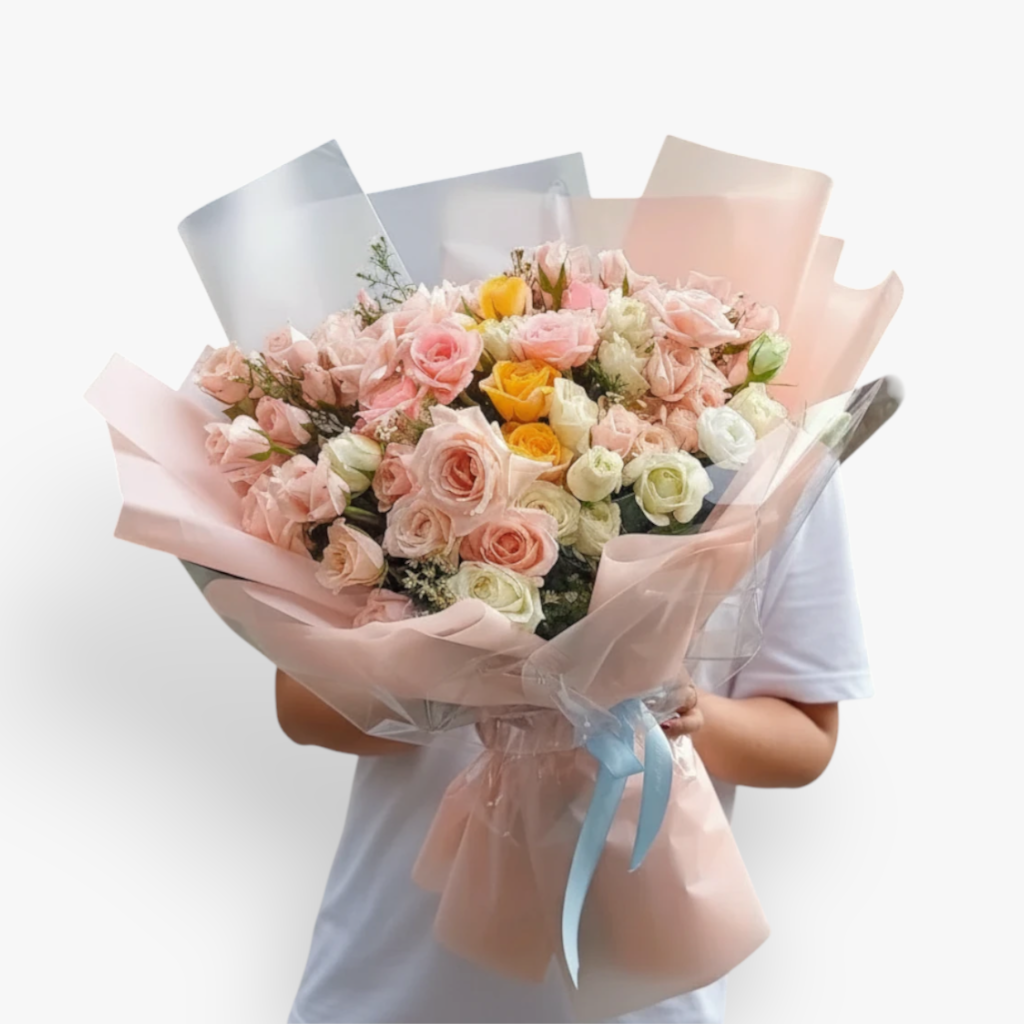 The Flowercart's Fior di Luna bouquet features pink, white, and yellow roses with baby's breath, wrapped in pink and silver paper.