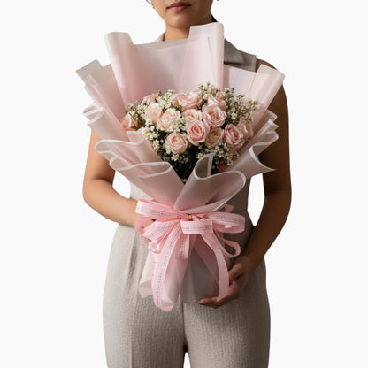 The Flowercart's California Dreaming bouquet: 24 soft pink roses with baby's breath, wrapped in pink paper and tied with a pink ribbon.