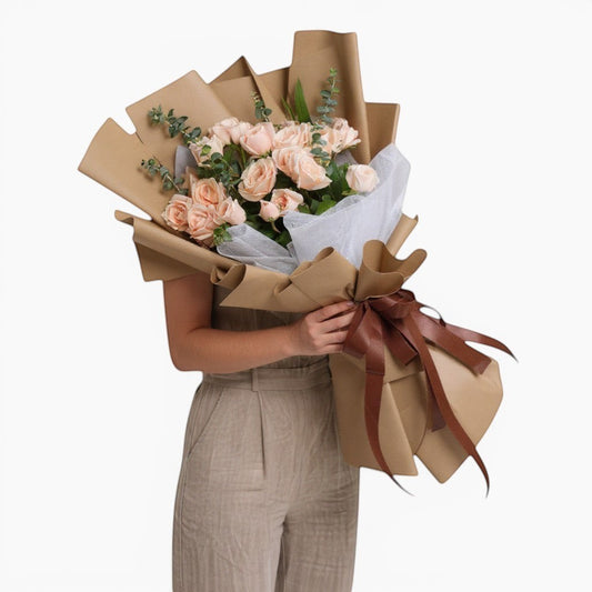 The Flowercart Terra Cotta bouquet features 24 soft pink roses and eucalyptus, wrapped in brown paper with a satin ribbon.