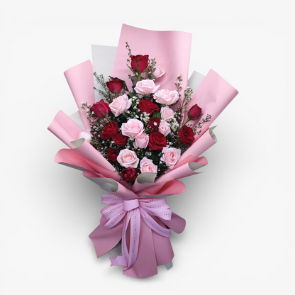 The Flowercart Sweet Romance bouquet: 24 red and blush pink roses with white fillers and greenery, wrapped in pink paper with a satin bow.