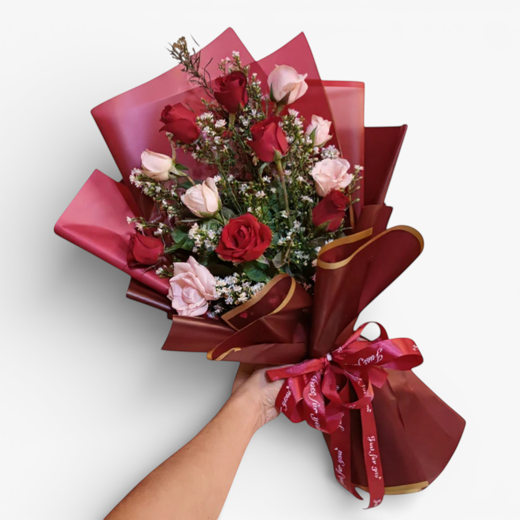 The Flowercart Sweet Heart Bouquet: 12 red and pink roses with baby's breath, wrapped in burgundy paper and ribbon.