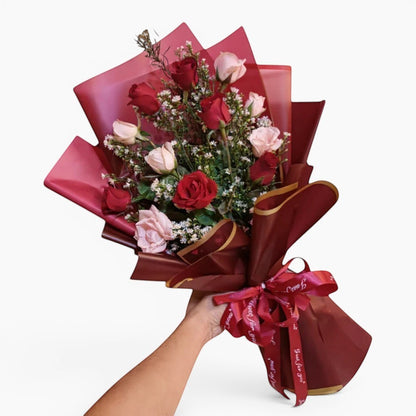 The Flowercart Sweet Heart Bouquet: 12 red and pink roses with baby's breath, wrapped in burgundy paper and ribbon.