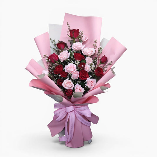 The Flowercart Sweet Romance bouquet: 24 red and blush pink roses with white fillers and greenery, wrapped in pink paper with a satin bow.