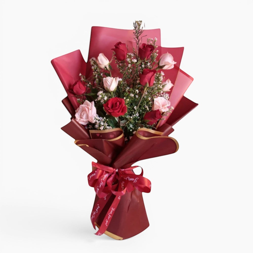 The Flowercart Sweet Heart Bouquet: 12 red and pink roses with baby's breath, wrapped in red paper and ribbon.