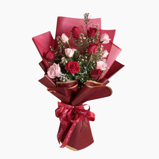 The Flowercart Sweet Heart Bouquet: 12 red and pink roses with baby's breath, wrapped in red paper and ribbon.