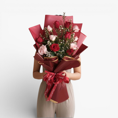 The Flowercart Sweet Heart Bouquet: 12 red and pink roses with baby's breath, wrapped in red paper and ribbon.