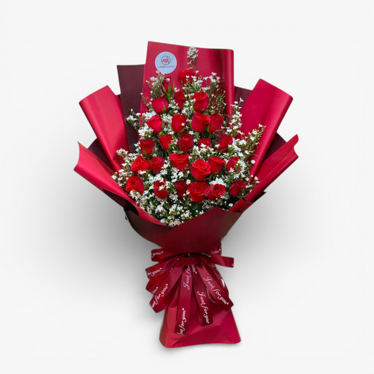 The Flowercart Valley Scent bouquet: 24 red roses with baby's breath, wrapped in red paper and ribbon.
