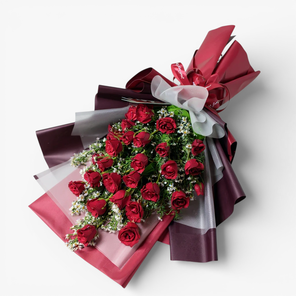 The Flowercart's Crimson Whisper bouquet: 24 red roses with white filler flowers, red ribbon, and gold heart accents.