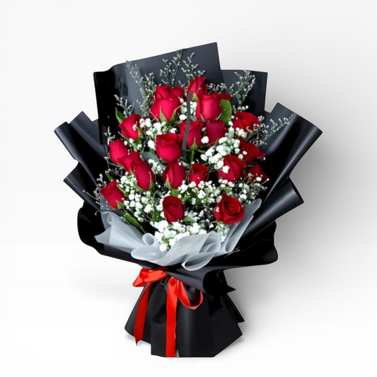 The Flowercart Luxe Noir bouquet: 24 red roses with white fillers, wrapped in black paper and tied with a red ribbon.