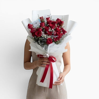 The Flowercart Fallin For You bouquet: 24 red roses with baby's breath and misty blue fillers, elegantly wrapped.