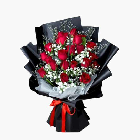 The Flowercart Luxe Noir bouquet: 24 red roses with white fillers, wrapped in black paper and tied with a red ribbon.