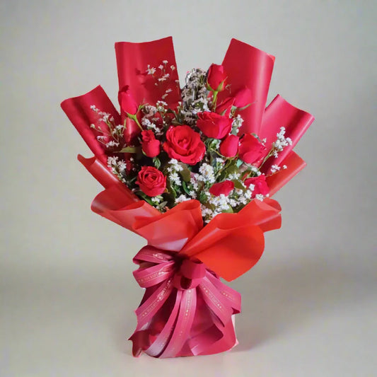 Bouquet of red roses with red and pink ribbons on a light gray background